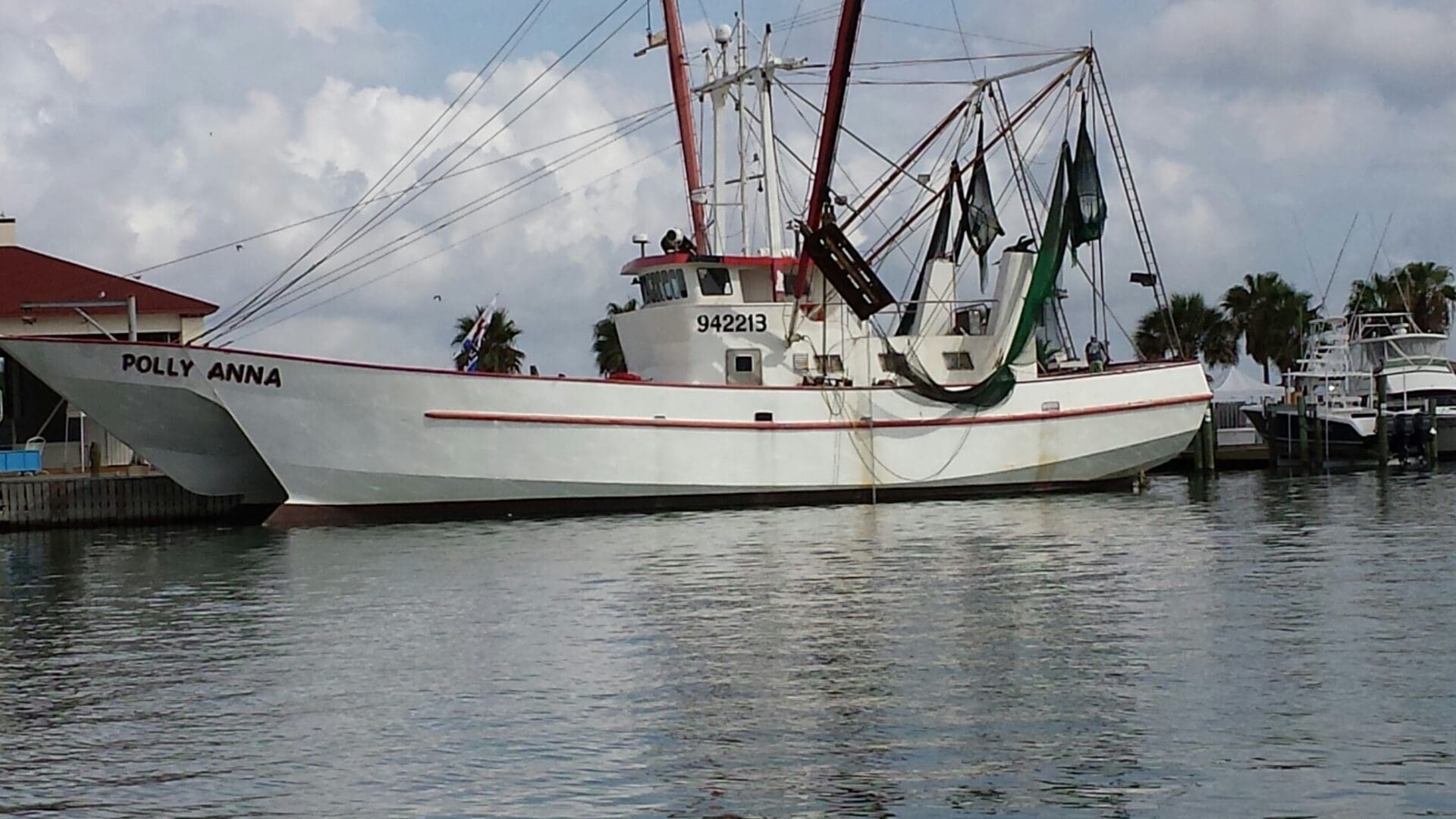 A white boat with two large nets on it's side.