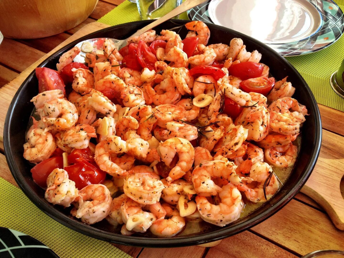 A pan of shrimp and tomatoes on the table.