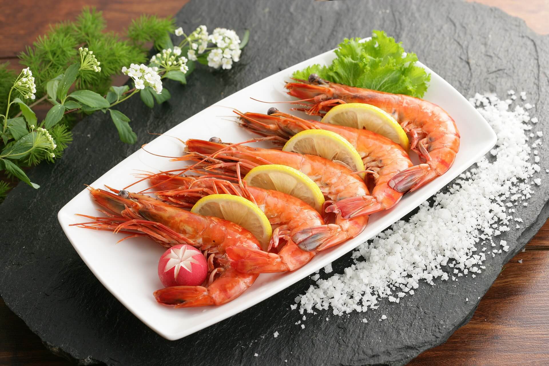 A plate of shrimp with lemon and herbs on it.
